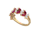 A yellow gold ring featuring marquise-cut and round-cut deep pinkish-red gemstones and small clear stones, shown on a plain white background.
